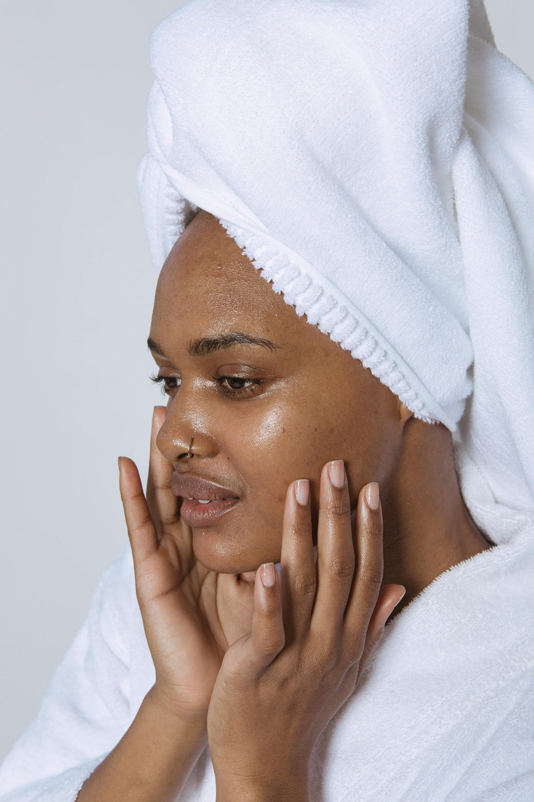 Femme appliquant un soin visage, bandeau blanc sur les cheveux