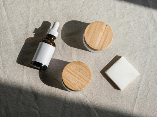 Flacon et pots de cosmétiques faits main posés sur du lin, avec un savon